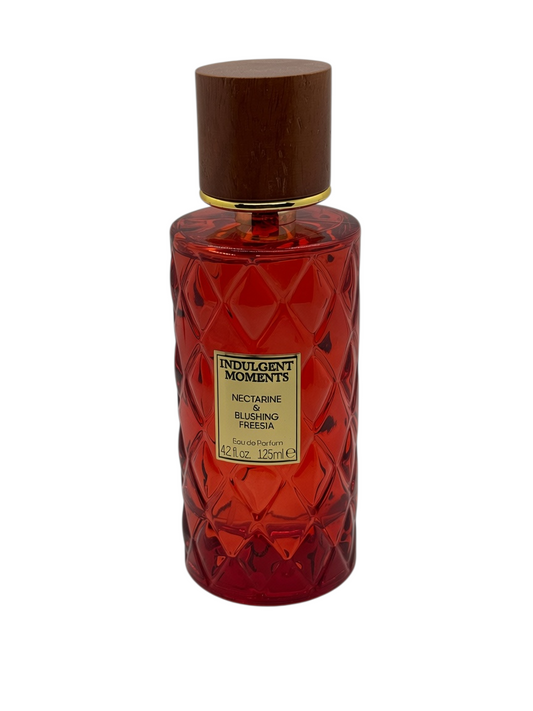 Paradime Enterprise LLC Indulgent Moments Nectarine & Blushing Freesia perfume in a red diamond-patterned glass bottle.