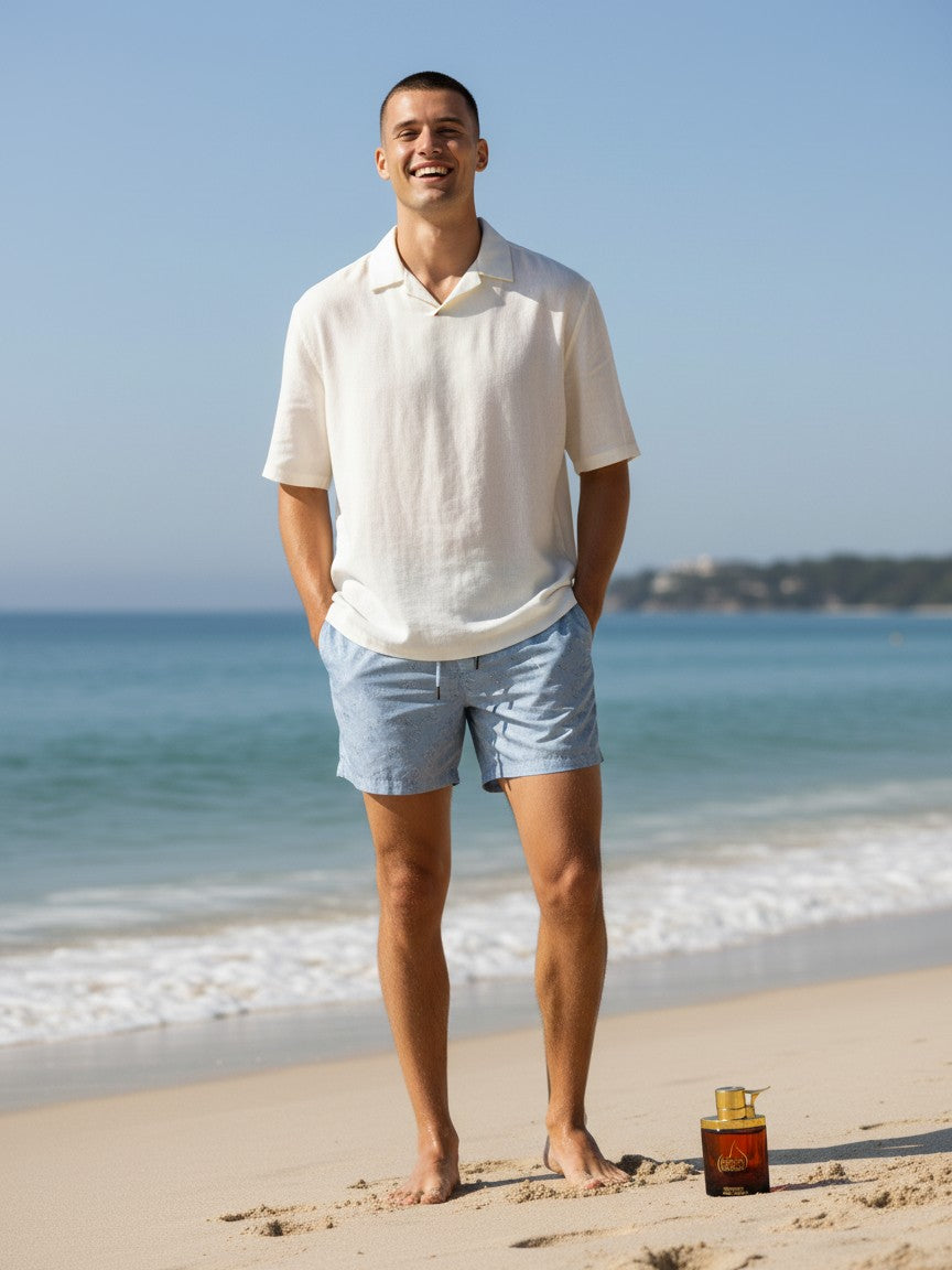 Paradime Enterprise LLC Manos De Fuego Caliente fragrance bottle on a sandy beach next to a smiling man in summer wear